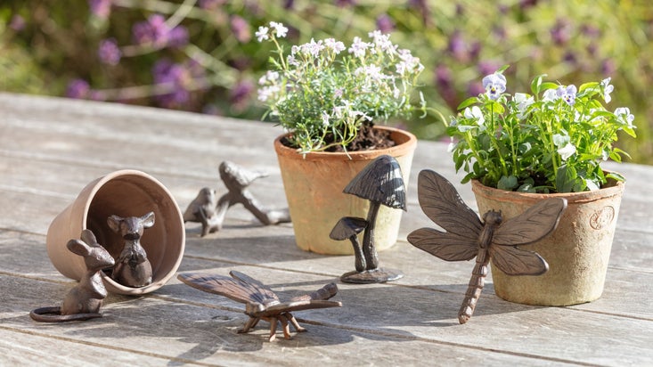 Cast iron sculptures of mice, dragonflies and mushrooms among plant pots